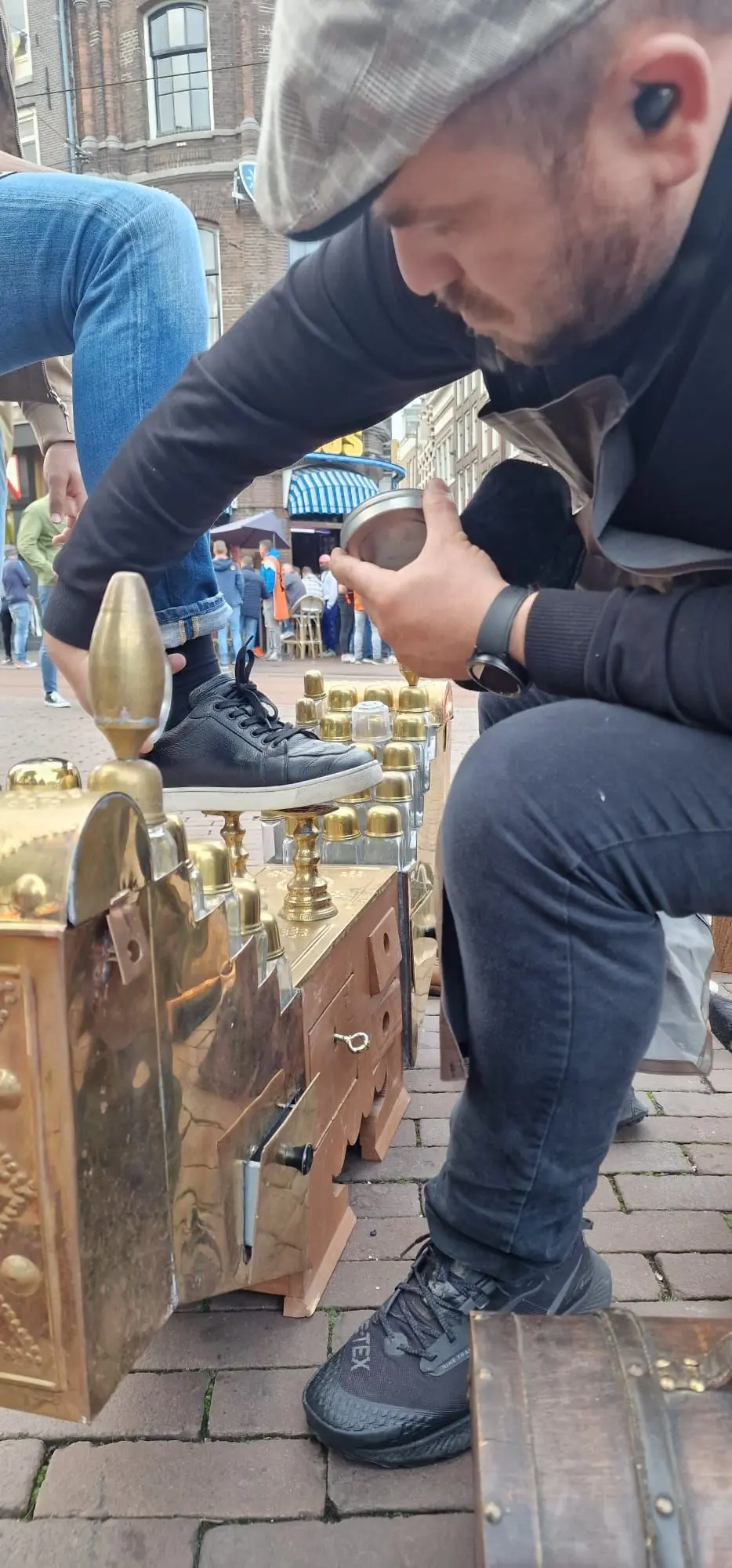 De Amsterdamse Schoenpoetser verzorgt een schoen op straat in Amsterdam